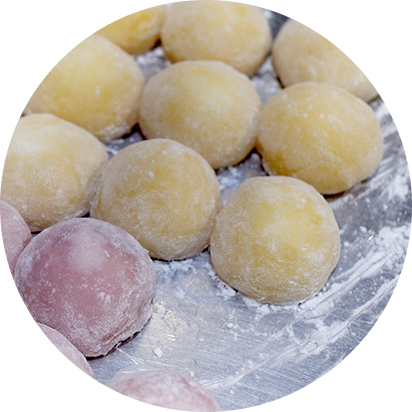 Assortiment de mochis sur un bol en bois, représentant diverses saveurs naturelles. Ces mochis 100% végétaux et sans gluten sont préparés à la main, illustrant lengagement de Lacigne pour une pâtisserie saine et artisanale.