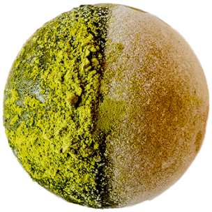 Mochi au thé vert matcha, coupé en deux pour révéler une garniture de pâte de haricot rouge, sur un fond noir.